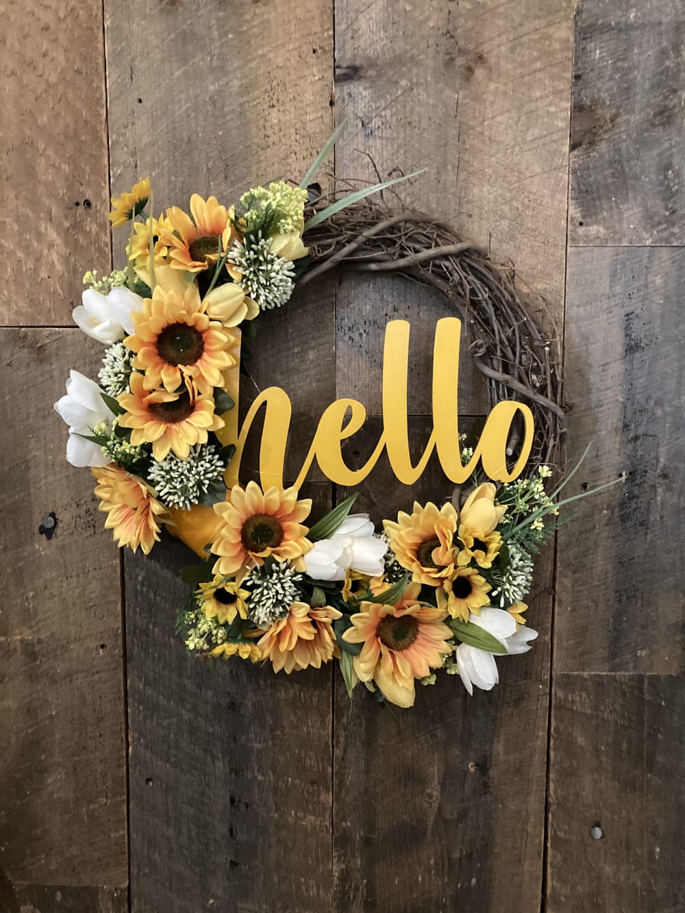 A sunflower grapevine wreath that says hello